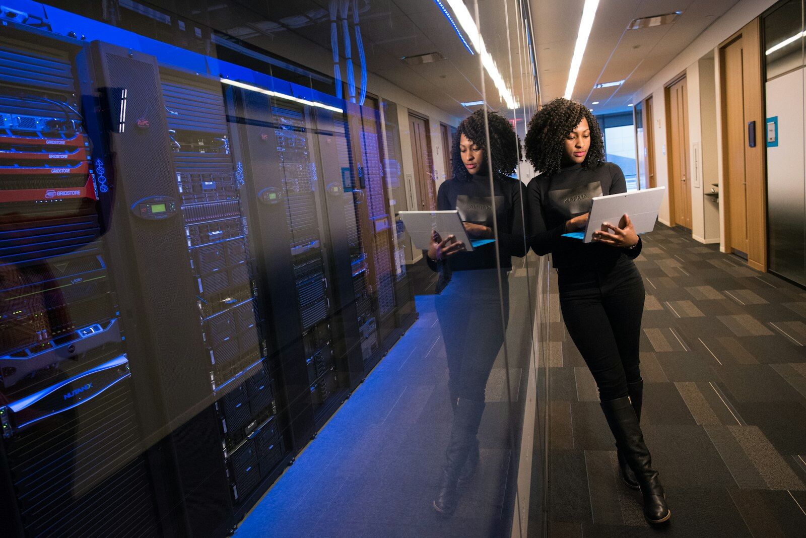 Security analyst with a laptop in a data-centre corridor, representing continuous security operations