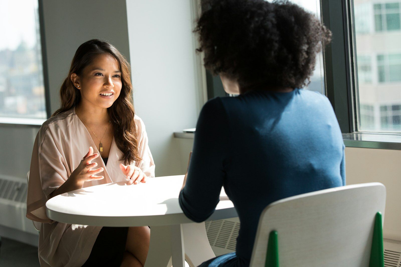 Two professionals in conversation at an office table, representing how Avisha Global teams work with clients